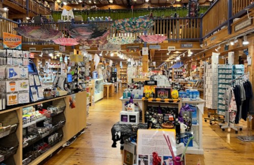A cozy store interior filled with various products, shelves, and colorful decorations hanging from the ceiling.