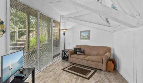 Cozy living space with a sofa, TV, and large windows letting in natural light.