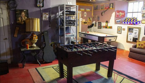 A cozy game room featuring a foosball table, a couch, and various decorations on the walls.