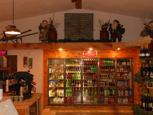 Interior of a store featuring a beverage cooler, shelves of snacks, and festive decorations on the walls.
