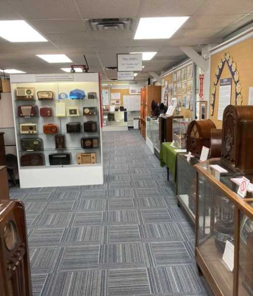 A museum hallway showcasing vintage radios in display cases, with informational panels on the walls.