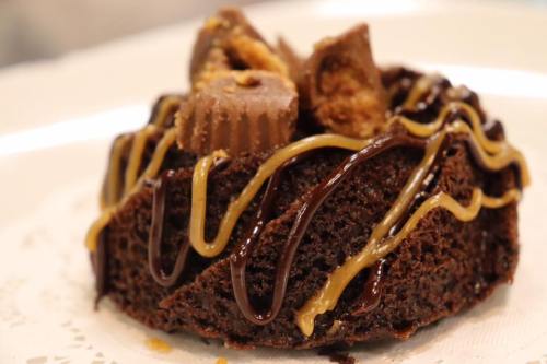 Close-up of a chocolate dessert topped with peanut butter cups and drizzled with chocolate and caramel sauces.
