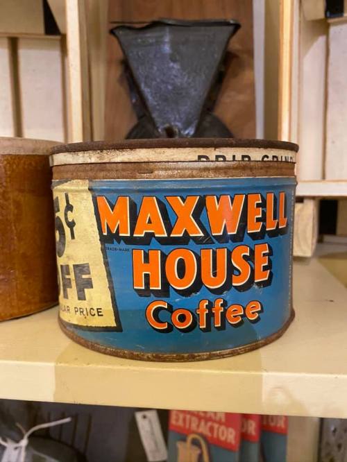 Vintage Maxwell House Coffee can with bold orange and blue design, displayed on a shelf among other items.