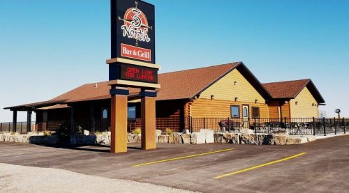 Exterior view of 3 North Bar & Grill, featuring a wooden building and a sign, with clear blue skies in the background.