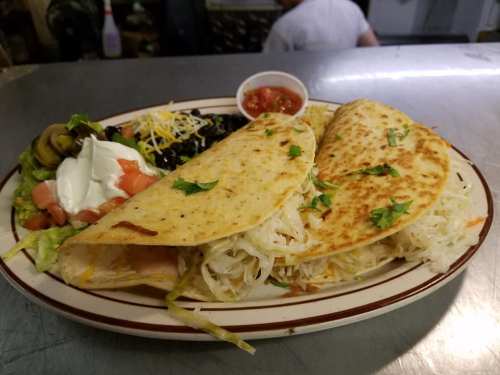 Two crispy tacos filled with shredded lettuce and cheese, served with a side of salad, sour cream, and salsa.