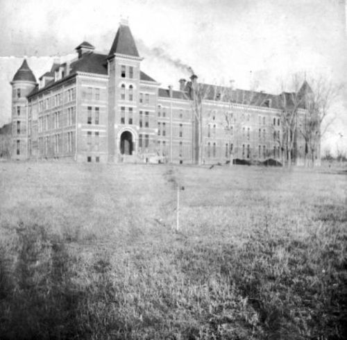 Historic building with multiple towers, set in a grassy area, captured in black and white.