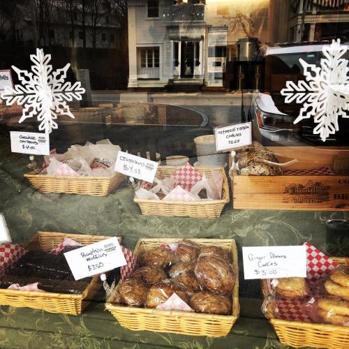 A bakery display featuring various baked goods in baskets, with snowflake decorations and price tags.
