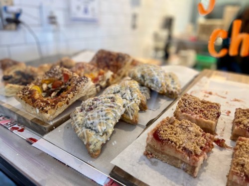 A display of assorted pastries, including fruit tarts, flaky pastries, and crumb-topped bars on parchment paper.