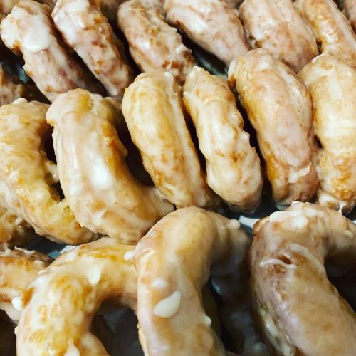 A close-up of glazed donuts stacked closely together, showcasing their golden-brown color and shiny icing.