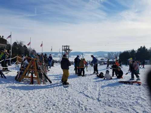 A snowy ski area with people skiing, snowboarding, and enjoying winter activities under a clear blue sky.