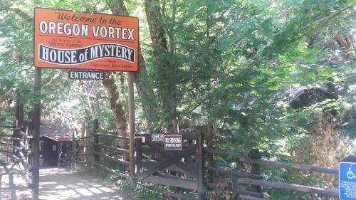 Sign for the Oregon Vortex and House of Mystery, surrounded by trees, indicating the entrance to the attraction.