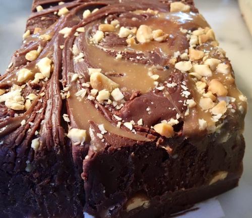 A close-up of a chocolate dessert topped with swirls of caramel and chopped nuts.