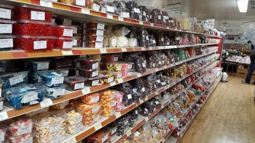 A colorful candy aisle filled with various types of sweets in clear packaging on shelves.