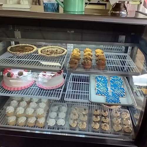 A display case filled with various desserts, including cakes, pies, cookies, and cupcakes, all beautifully arranged.