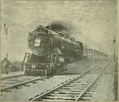 A vintage steam locomotive chugs along tracks, with smoke billowing and a train car trailing behind.