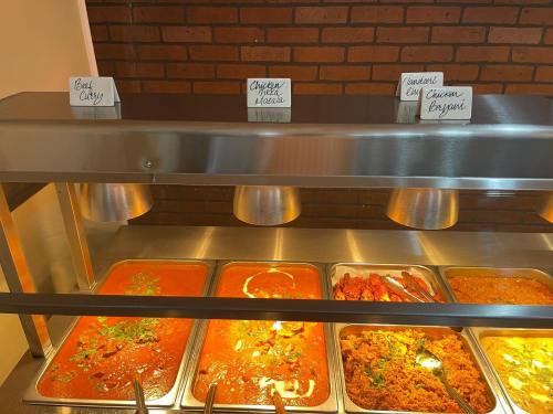 A buffet display with three trays of food: beef curry, chicken tikka masala, and chicken biryani, labeled on white cards.