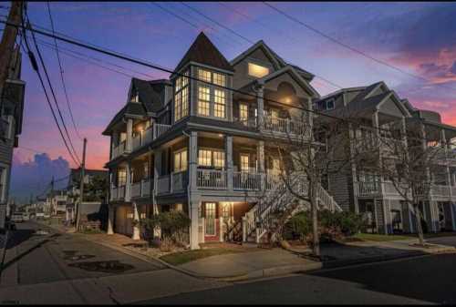 A charming multi-story house at sunset, featuring balconies and a peaked roof, with a colorful sky in the background.