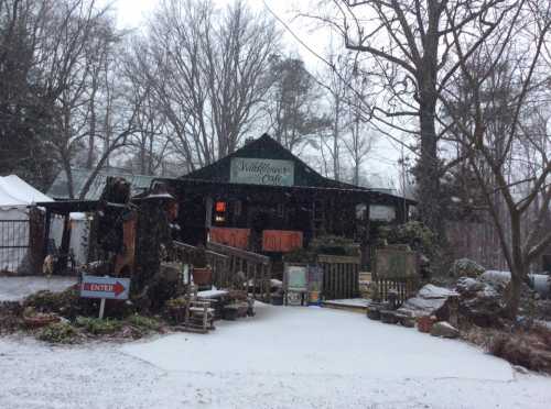 A cozy café surrounded by trees, with snow covering the ground and a welcoming entrance sign.