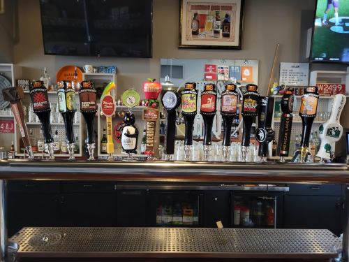 A bar with a variety of beer taps lined up, showcasing colorful labels and different brands.