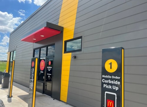 Exterior of a McDonald's with a curbside pickup area and bright yellow and red accents on the building.