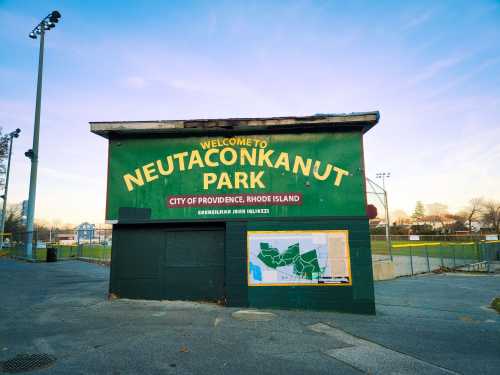 Sign welcoming visitors to Neutaconkanut Park in Providence, Rhode Island, with a map and sports fields in the background.