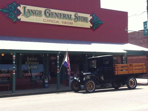 A vintage truck parked in front of the Lange General Store, established in 1908, with colorful signage and candy barrels.