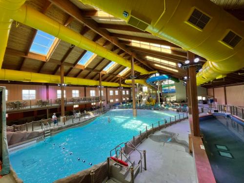 Indoor water park featuring a large pool, water slide, and wooden beams with natural light streaming in.