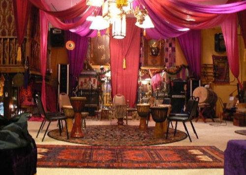 A cozy, colorful room with draped fabric, drums, and a patterned rug, creating an inviting atmosphere for gatherings.