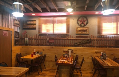 Cozy restaurant interior with wooden tables, rustic decor, and vintage signs on the walls. Warm lighting enhances the atmosphere.