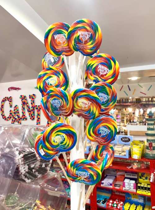 A colorful display of rainbow swirl lollipops on sticks, arranged in a cheerful, vibrant setting.