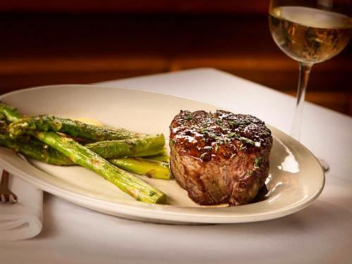 A perfectly cooked steak on a plate, accompanied by asparagus and a glass of white wine.
