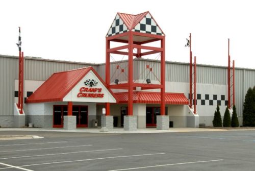 Exterior of Crane's Cruisers, featuring a red and white checkered roof and tall tower, with a parking lot in front.