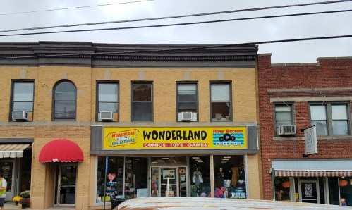 A storefront with a bright yellow sign reading "Wonderland Comics Toys Games" and a red awning nearby.