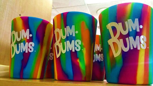 Colorful, striped cups with the text "Bum Bums" displayed on a wooden surface.