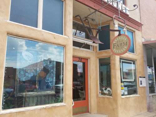 Exterior of a restaurant called "The Farm," featuring a rustic facade and large windows with artwork.