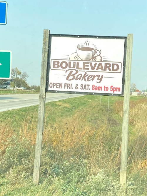 Sign for Boulevard Bakery, open Friday and Saturday from 8 AM to 5 PM, located by a roadside.