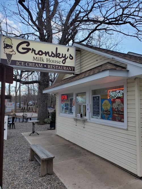 Exterior of Gronsky's Milk House, an ice cream restaurant, featuring an "OPEN" sign and outdoor seating.