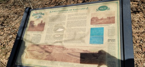 Historical marker detailing a WWII prisoner of war camp, featuring text and images about its history and significance.