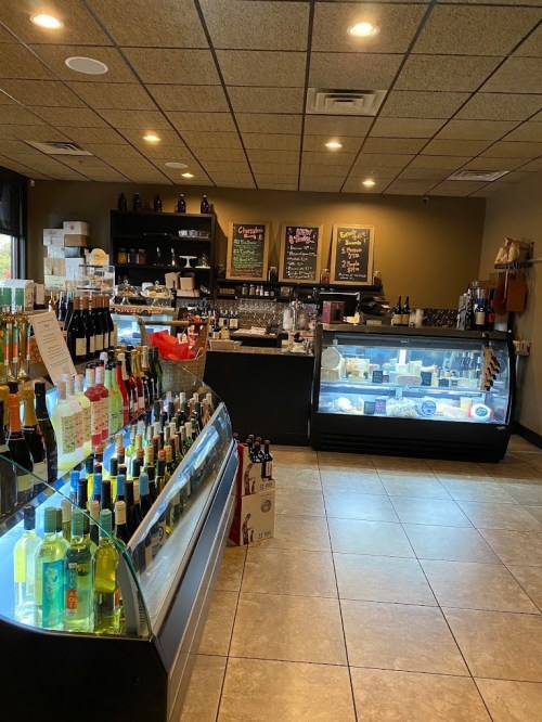 Interior of a store featuring shelves of beverages, a display case with food items, and chalkboard menus on the wall.