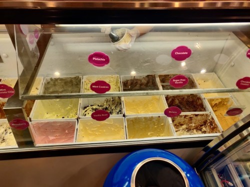 A display case filled with various ice cream flavors, including pistachio, chocolate, and mint cookies.