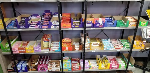 Shelves filled with various candy bars and snacks in colorful packaging, organized by type and brand.