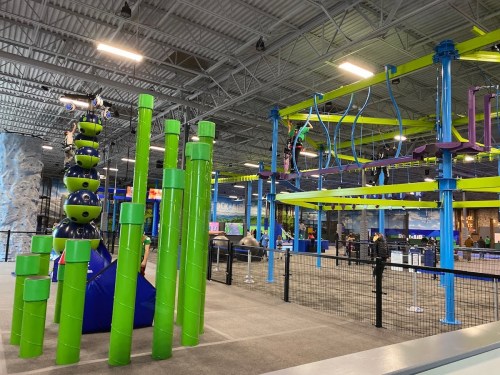 Indoor adventure park featuring climbing structures, a ropes course, and colorful play equipment.