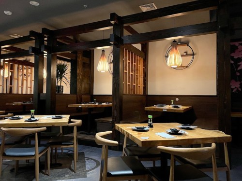 A cozy restaurant interior featuring wooden tables, stylish lighting, and partitioned seating areas.