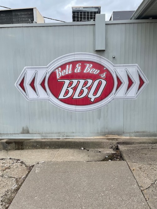 Mural of "Bett & Bev's BBQ" on a wall, featuring a red and white design with arrows.