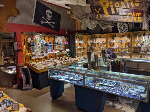 A vibrant display of gemstones and minerals in a pirate-themed shop, featuring glass cases and decorative elements.
