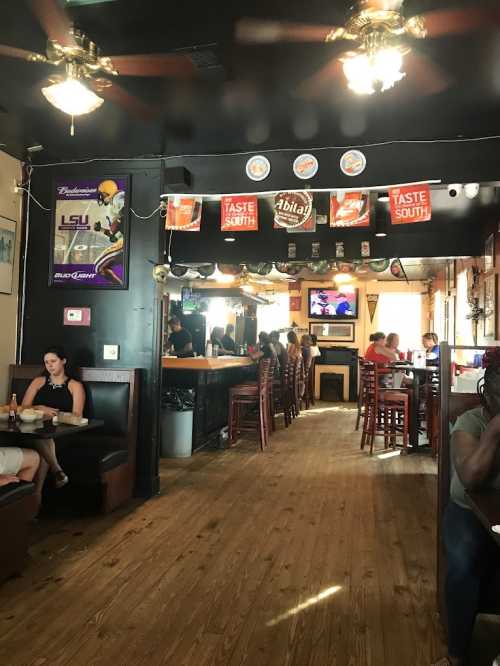 Interior of a lively restaurant with wooden floors, booths, and a bar, featuring sports memorabilia and patrons dining.