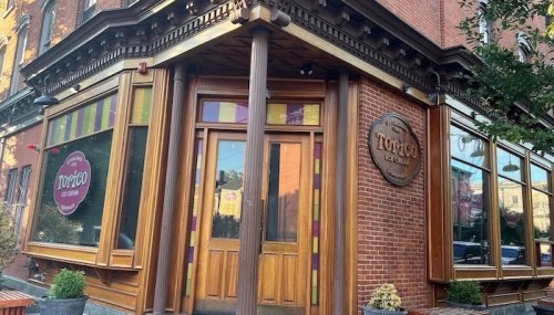 Exterior of a brick building featuring large windows and a wooden entrance, labeled "Tortico Ice Cream."