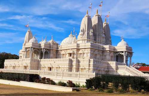 A stunning white temple with intricate carvings and domes, set against a blue sky.