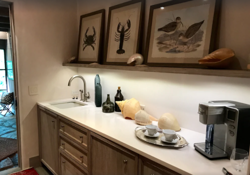 A modern kitchen counter with framed seafood art, a coffee machine, and decorative shells on display.