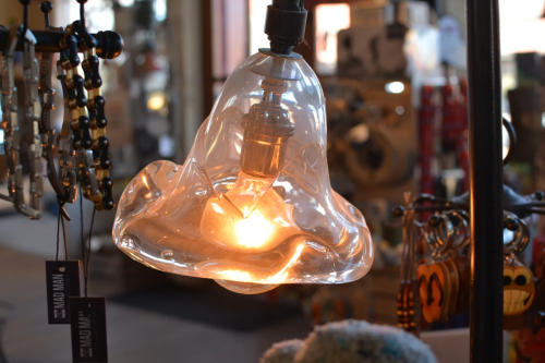 A unique, translucent glass pendant light with a warm glow, hanging in a stylish store setting.